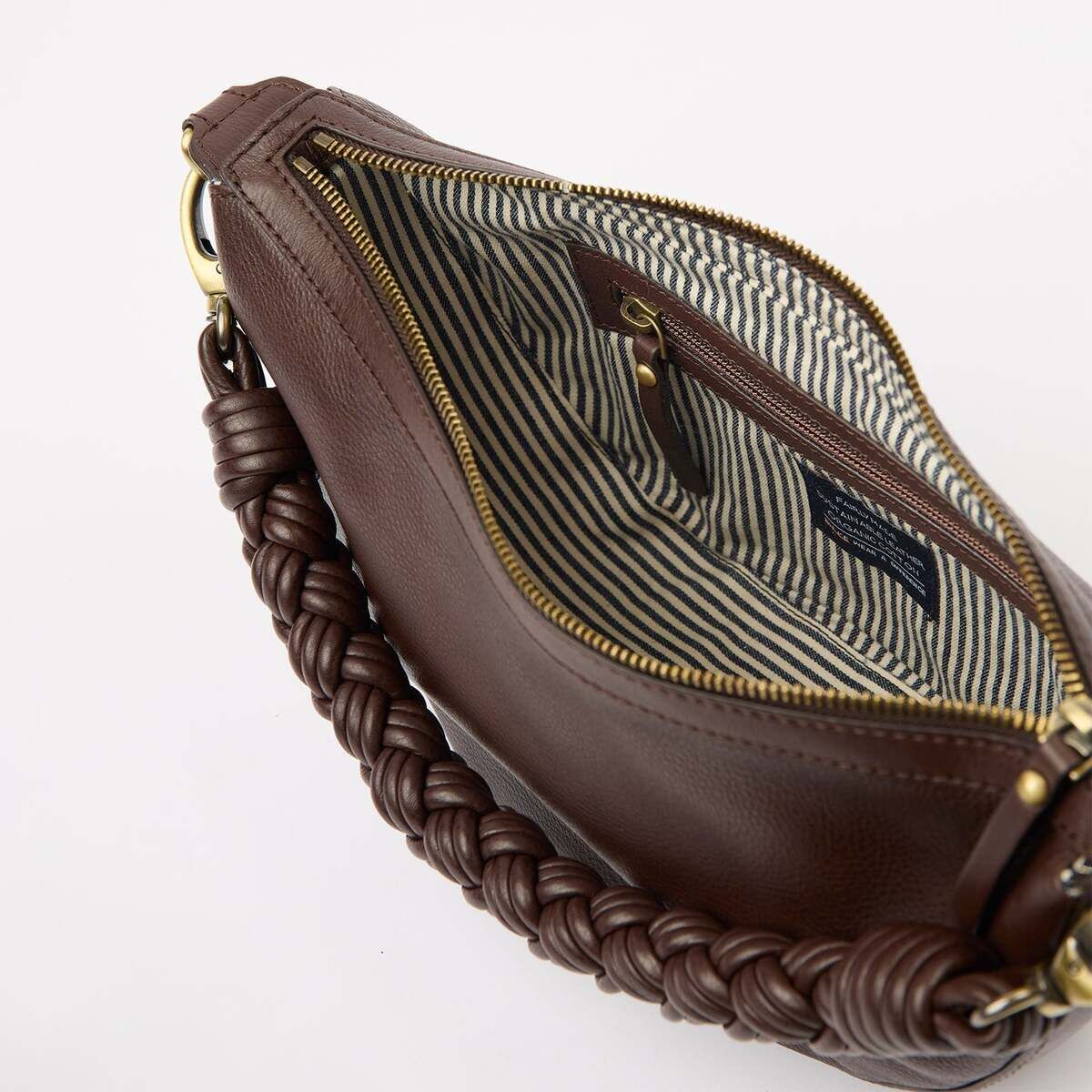 Nahaufnahme einer braunen Handtasche mit geflochtenem Henkel, goldfarbenem Reißverschluss und gestreiftem Innenfutter. Die Tasche ist leicht geöffnet und zeigt das geräumige, elegante Innenleben mit einer kleinen Innentasche.