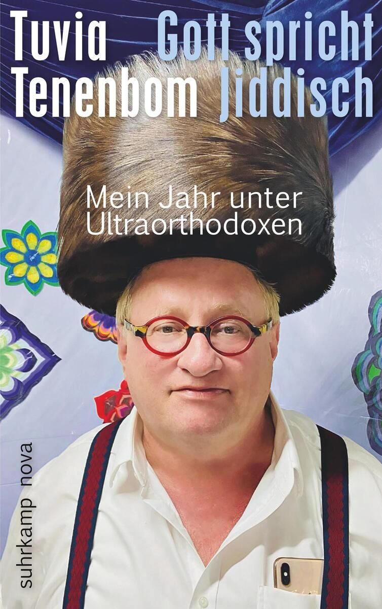 Das Buchcover zeigt einen Mann mit Brille und traditioneller jüdischer Kopfbedeckung vor einem bunten Hintergrund. Der Titel des Buches lautet: 'Gott spricht Jiddisch: Mein Jahr unter Ultraorthodoxen' von Tuvia Tenenbom. Es ist bei Suhrkamp Nova erschienen.