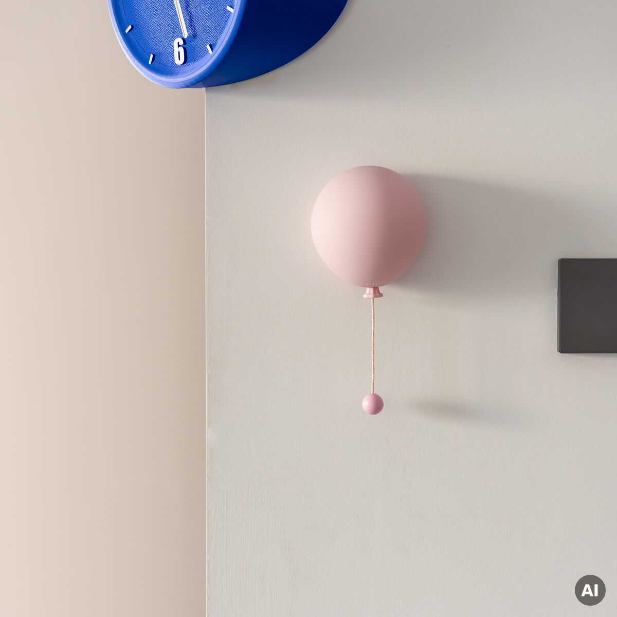 An einer hellen Wand hängt die Leuchte »Mimo Ballon« von Gingko Design Ltd in blush bloom. Die Lampe hat die Form eines rosa Ballons mit kleinem Zugseil. Darüber befindet sich eine blaue Wanduhr. Das Bild zeigt ein modernes, minimalistisches Wohnambiente.