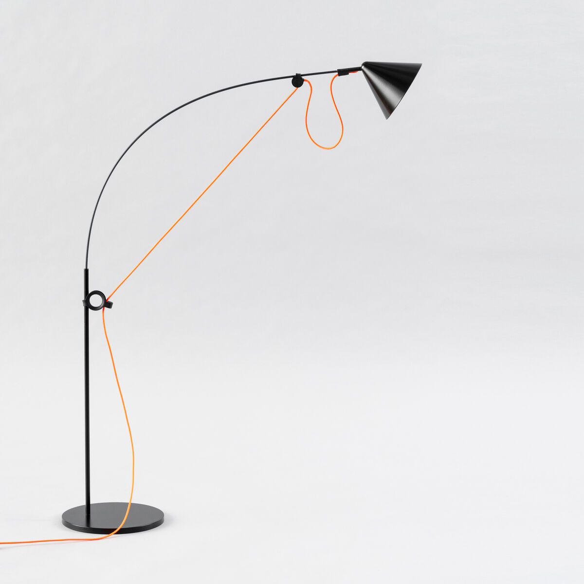 Eine moderne Tischlampe namens »AYNO« mit einem schwarzen Körper und einem orangefarbenen Kabel. Die Lampe hat ein minimalistisches Design mit einer verstellbaren Struktur.