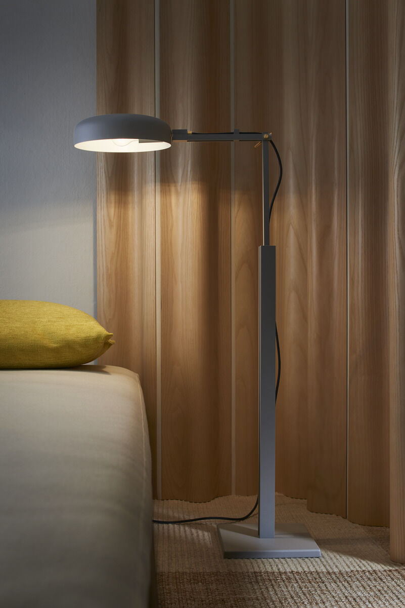 Moderne Stehleuchte »schliephacke« in einem Raum mit Holzwänden und einem Bett. Die Lampe hat ein minimalistisches Design und beleuchtet einen Teil des Raumes mit warmem Licht.