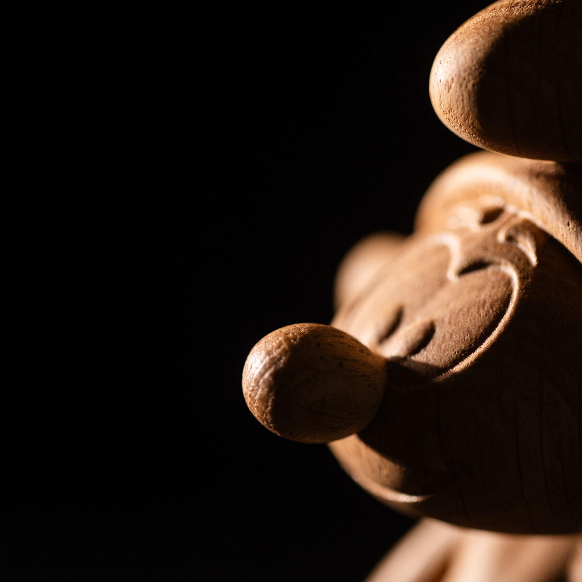 Nahaufnahme einer handgefertigten Holzfigur eines Schlümpfs, detailreich geschnitzt, auf einem dunklen Hintergrund präsentiert.