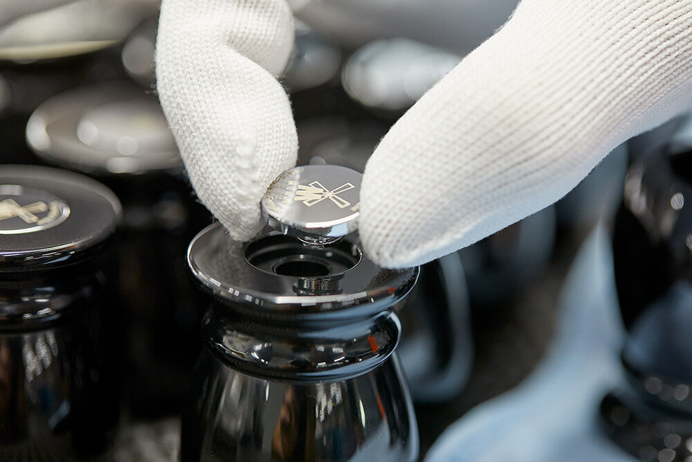 Nahaufnahme von zwei behandschuhten Händen, die einen Rasierhobeldeckel auf ein schwarzes Rasiererset-Behältnis setzen.