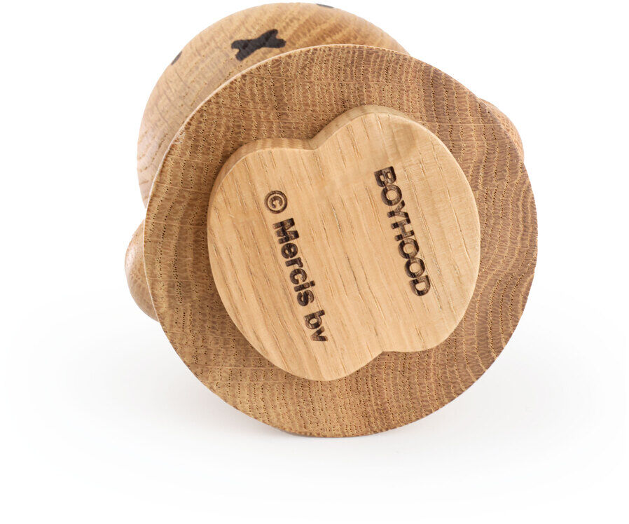 Die Abbildung zeigt eine stehende Holzfigur aus hellem, naturbelassenem Holz in Form der bekannten Figur Miffy. Die Figur liegt auf dem Rücken, sodass die Unterseite sichtbar ist. Dort sind verschiedene Gravuren, darunter das Boyhood-Logo und ein kleiner Miffy-Umriss, deutlich zu sehen.