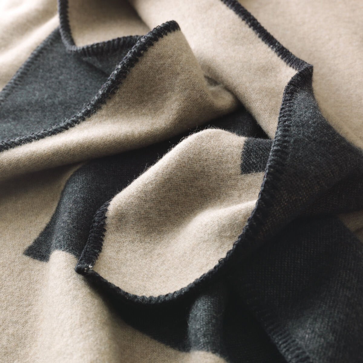Nahaufnahme einer Kaschmirdecke, die in Schwarz und Beige gehalten ist. Die Decke ist luxuriös und weich, ideal für gemütliche Abende.
