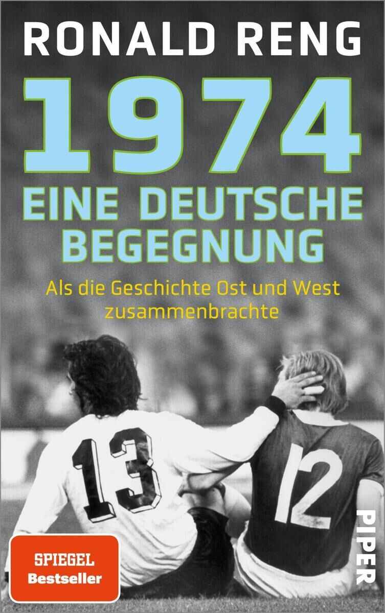 Das Buchcover von '1974 - Eine deutsche Begegnung' von Ronald Reng zeigt zwei Fußballspieler, die sich auf dem Spielfeld umarmen, mit der Aufschrift: 'Als die Geschichte Ost und West zusammenbrachte'.