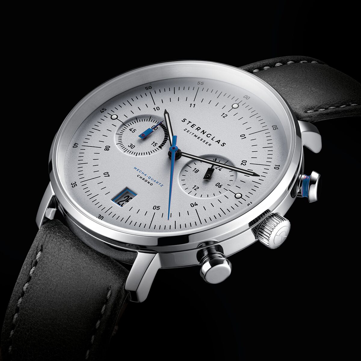 Detailreiche Aufnahme der ZEIT-Sonderedition Uhr »Hamburg Chronometer« von Sternglas. Die Armbanduhr hat ein silbernes, gewölbtes Zifferblatt mit feinen schwarzen Indizes, blauen Details und einem schwarzen Bridle-Lederarmband. Das Gehäuse besteht aus poliertem Edelstahl, die Zeiger sind filigran.