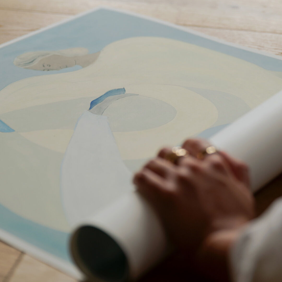 Abstraktes Gemälde von Sofia Lind in Blautönen, das eine minimalistische, ruhige Szene zeigt, eingerahmt und auf einem Holzboden liegend, mit einer Hand, die das Bild ausrollt.