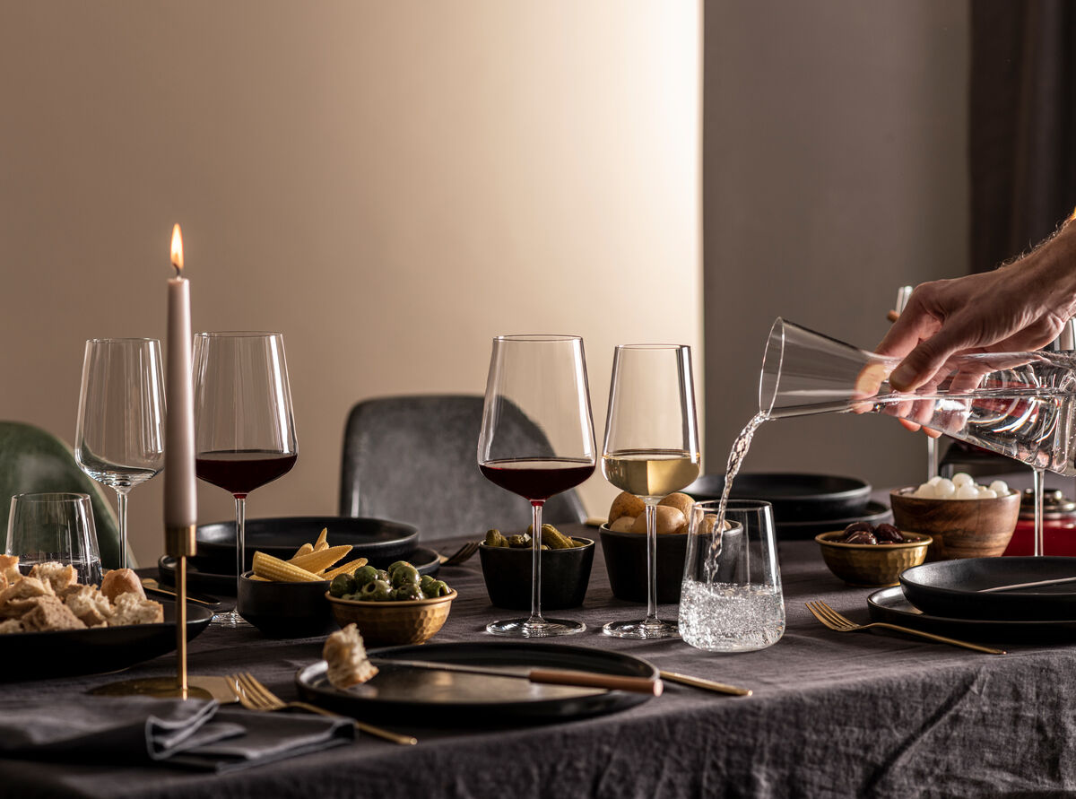 Eine elegante Tischszene mit verschiedenen Weingläsern des Sommelier-Bundles 'Vervino', umgeben von Kerzenlicht und Tellern, mit einem Fokus auf Weinliebhaber.