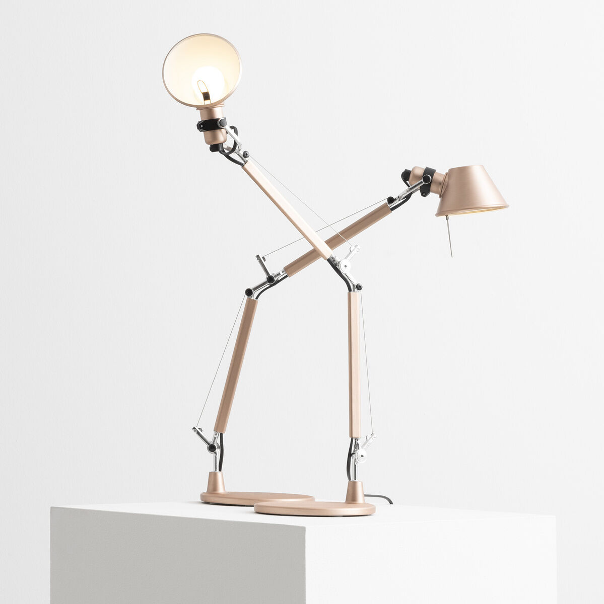 Die Artemide »Tolomeo Micro« ist eine moderne, verstellbare Tischlampe in minimalistischen Farbtönen. Das Design beinhaltet mehrere Schwenkarme aus Aluminium, die auf einem weißen, rechteckigen Podest präsentiert werden.