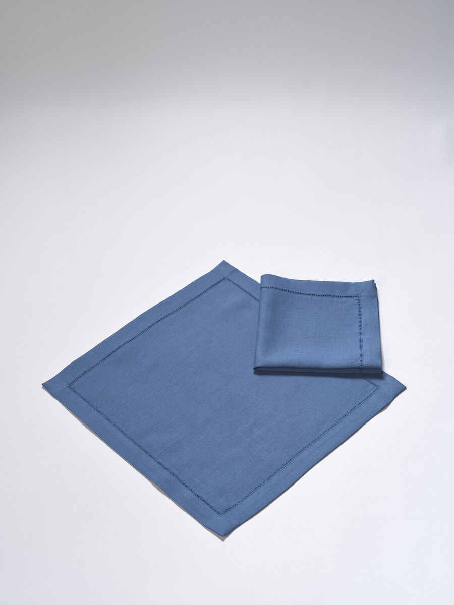 Zwei blaue Leinen-Servietten, eine offen und eine gefaltet, auf einem hellen Hintergrund.