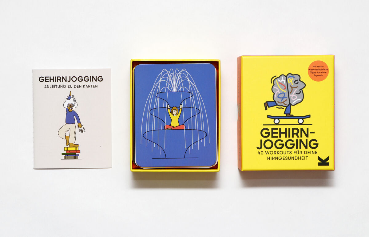 Ein Gedächtnisspiel namens »Gehirnjogging« auf einer weißen Oberfläche. Es besteht aus einem gelben Karton mit einer Illustration eines Gehirns auf einem Skateboard, einer Anleitung und einem Stapel blauer Karten. Die Illustration zeigt eine Person auf einem Bücherstapel und eine Person, die eine Statue imitiert.