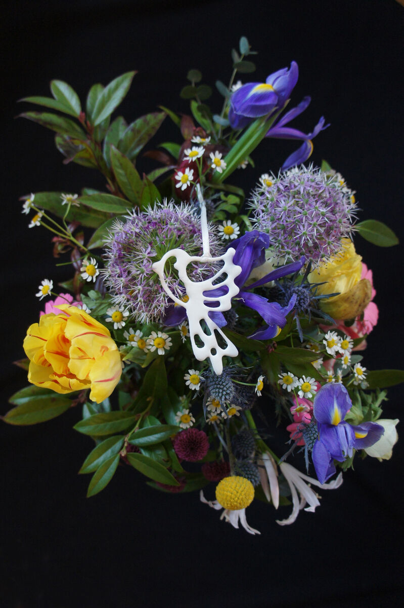 Ein dekorativer Blumenstrauß mit einer Vielzahl farbenfroher Blumen und sechs kleinen Porzellanvögeln, die darin verstreut sind. Der Hintergrund ist schwarz, was die Farben und Details des Straußes und der Vögel hervorhebt.