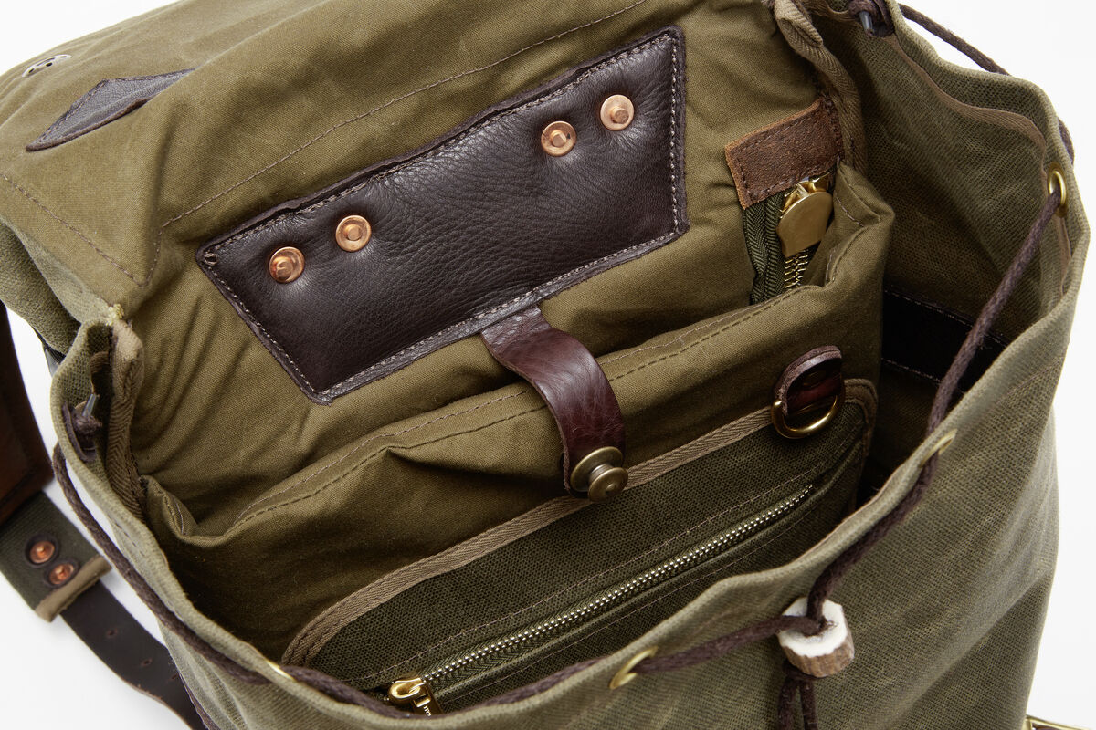 Großer Canvas-Rucksack mit mehreren Fächern, darunter eine Innentasche mit Reißverschluss. Lederdetails und Metallknöpfe; Farben sind Braun, Olivgrün und Gold.