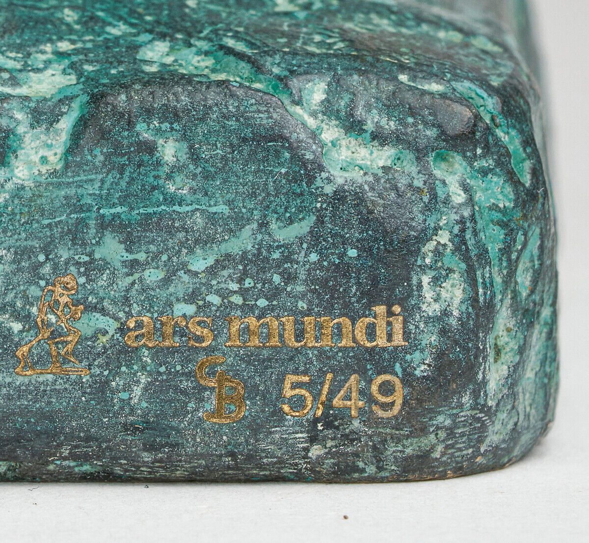 Die Skulptur »Lesefreuden« von Gerhard Brandes zeigt eine detailreiche Figur aus Bronze, die in einem Grünton gehalten ist. Die Oberfläche hat eine patinierte Struktur mit goldfarbenen Akzenten.