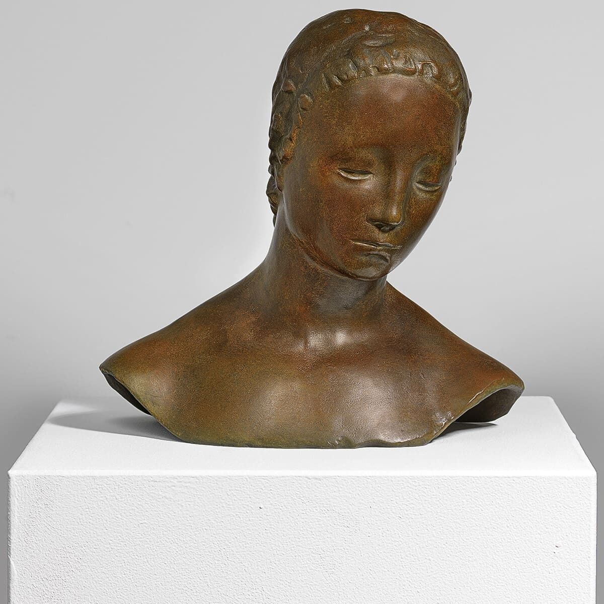 Eine Bronzeskulptur von Wilhelm Lehmbruck mit dem Titel »Gesekter Frauenkopf« aus dem Jahr 1910. Die Büste zeigt einen weiblichen Kopf, der nach unten geneigt ist, und steht auf einem weißen Sockel.