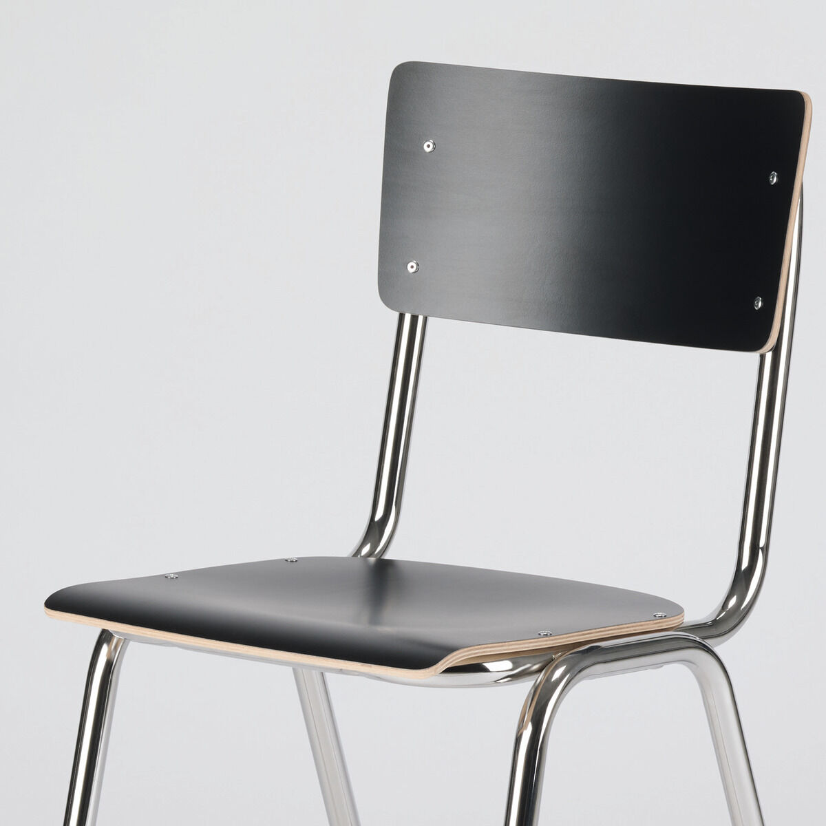 Der Stuhl »ZERO« von Jan Kurtz in der ZEIT-Sonderedition zeigt eine Sitzfläche und Rückenlehne aus schwarz beschichtetem Furnier, kombiniert mit einem poliertem Chromgestell. Die Proportionen sind schlicht, das Design modern und minimalistisch, ohne Verzierung.