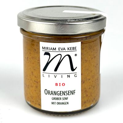Das Bild zeigt ein rundes Glas mit silbernem Metalldeckel, gefüllt mit orangefarbenem Bio-Orangensenf. Auf dem Glas ist ein weißes Etikett mit schwarzem Schriftzug: 'Miriam Eva Kebe', 'Living', 'BIO', 'Orangensenf grober Senf mit Orangen' zu sehen.